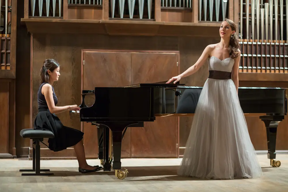 Woman pianist playing the piano with a beautiful singer standing next to her.