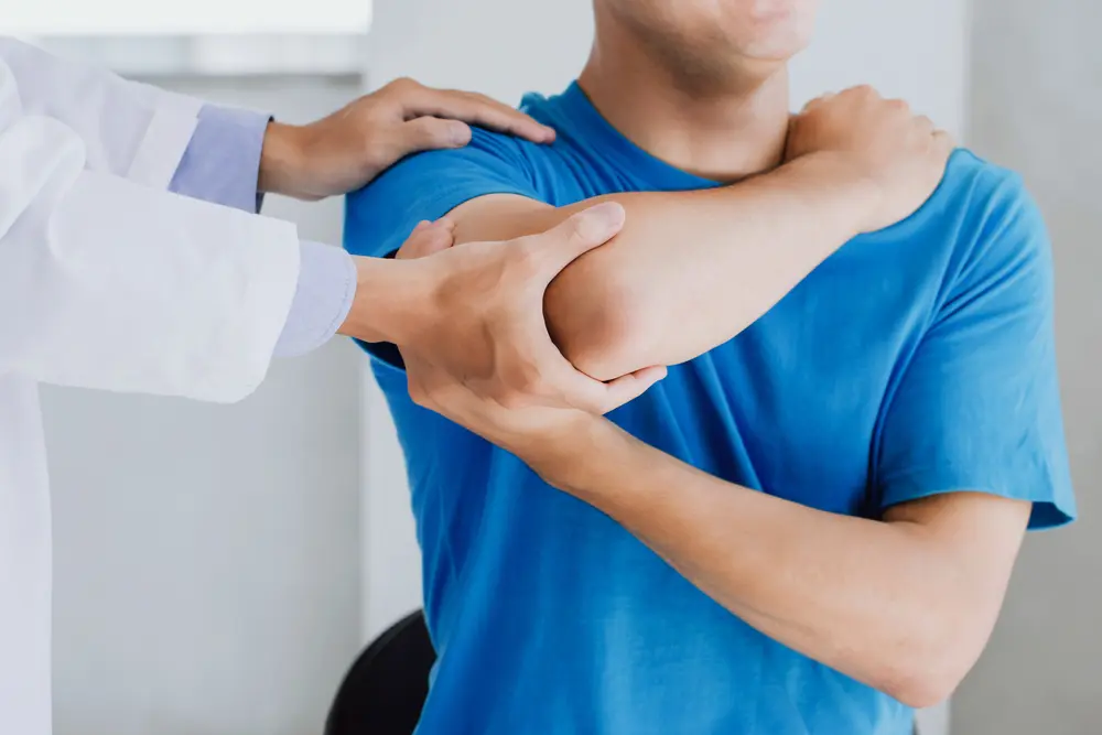 Professional physiotherapists providing assistance to male patients with arm injuries.